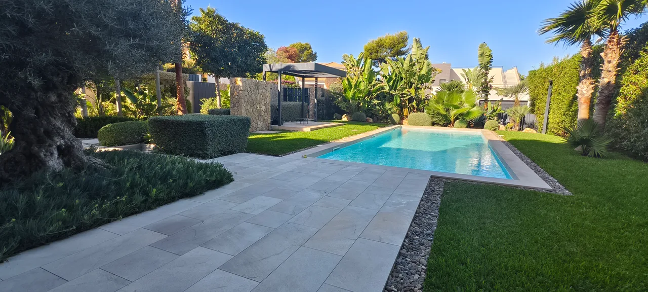 Piscina con terraza de piedra y césped en una villa de Mallorca