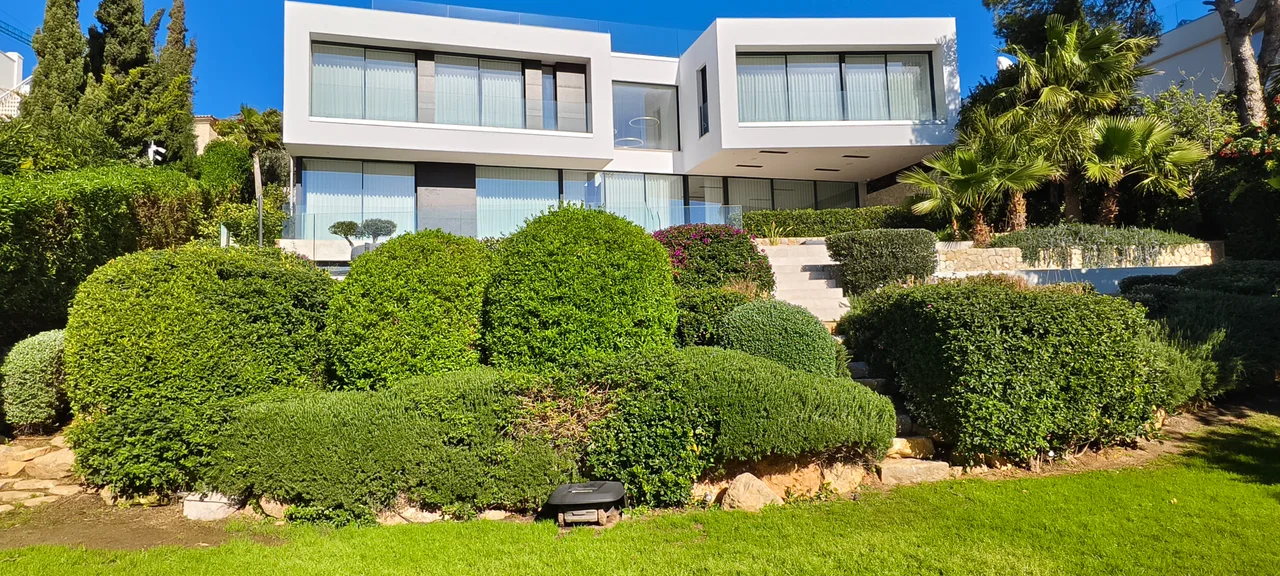 Jardin de bolas de boj recortadas frente a una villa moderna